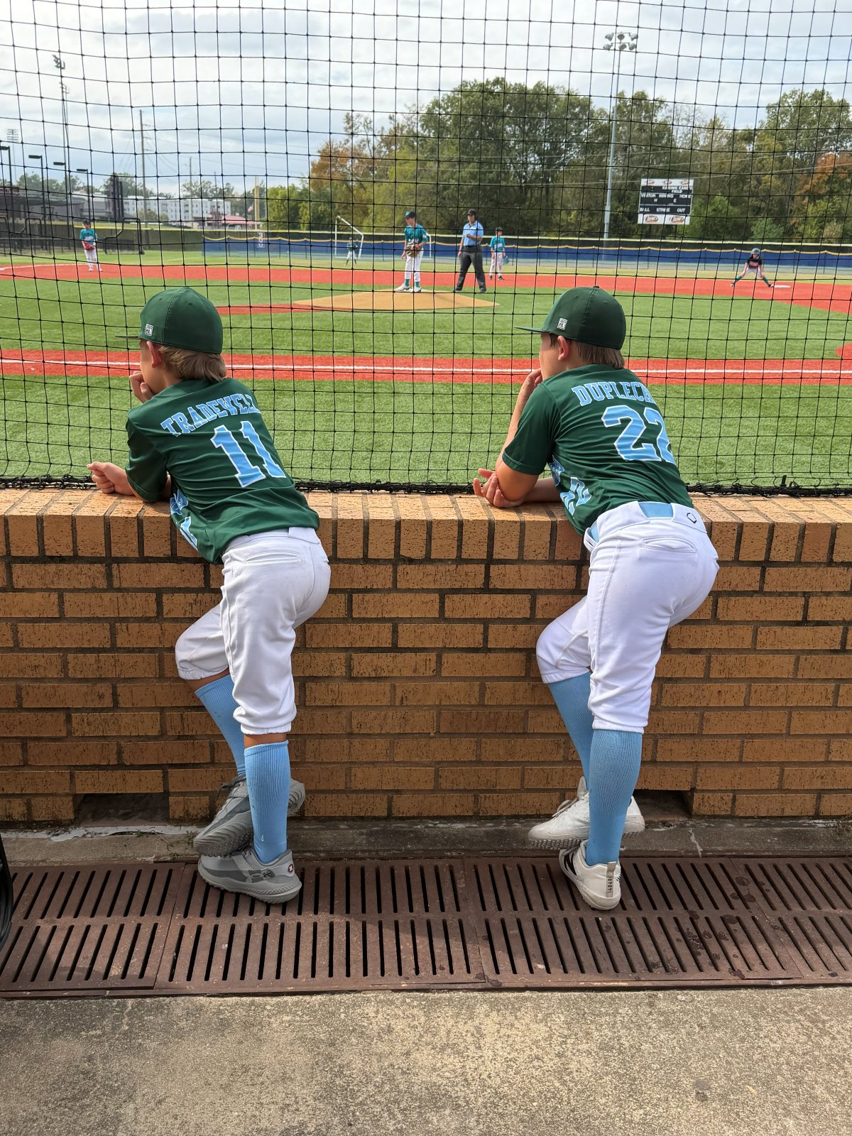 Two players watching the game from the dugout wall